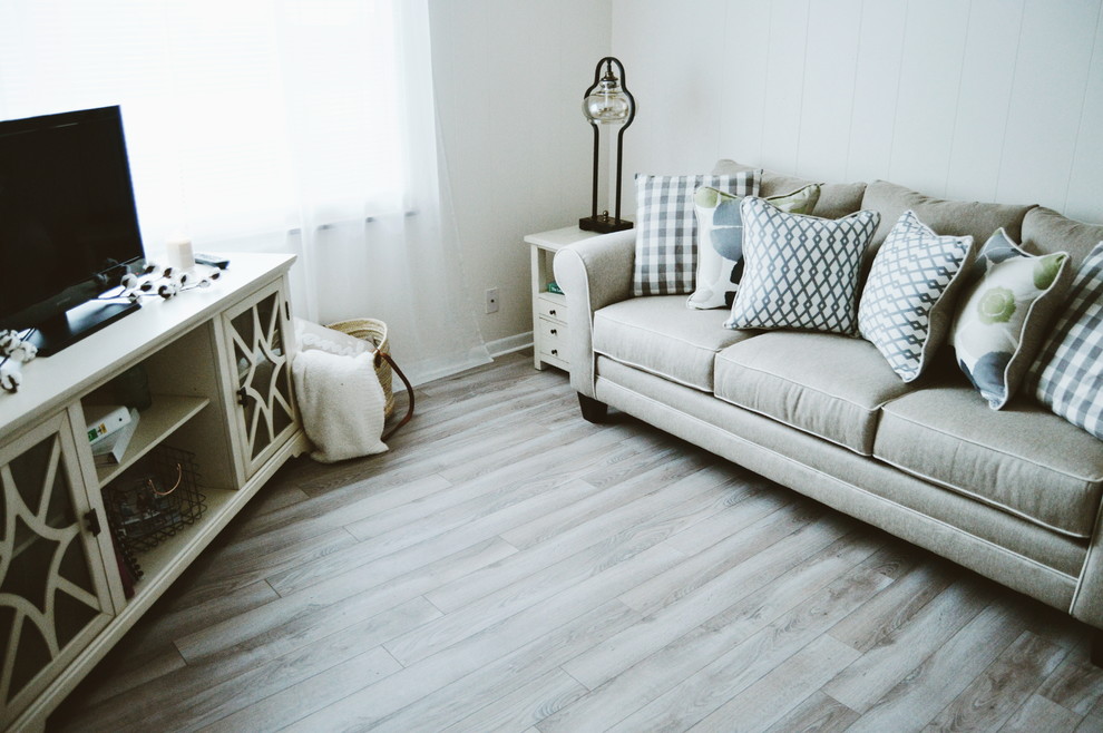 Kleines, Abgetrenntes Country Wohnzimmer mit weißer Wandfarbe, hellem Holzboden, freistehendem TV und braunem Boden in New York