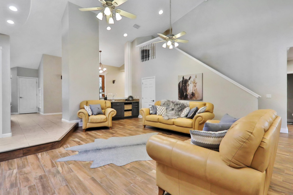 Geräumiges, Offenes Landhaus Wohnzimmer ohne Kamin mit weißer Wandfarbe, freistehendem TV, braunem Boden und Keramikboden in Jacksonville