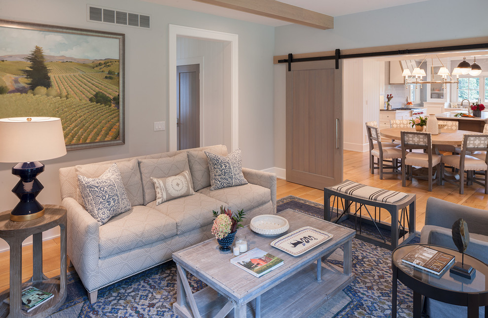 Modelo de salón abierto de estilo de casa de campo de tamaño medio con paredes azules, suelo de madera clara y suelo beige