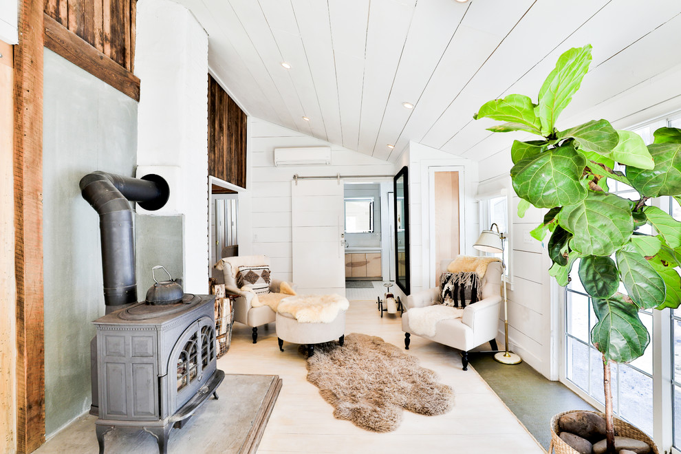 Aménagement d'un salon campagne fermé avec une salle de réception, un mur blanc, parquet clair, un poêle à bois, aucun téléviseur, un sol beige et un manteau de cheminée en béton.