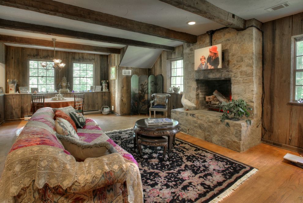 На фото: гостиная комната в стиле кантри с стандартным камином, фасадом камина из камня и коричневыми стенами с