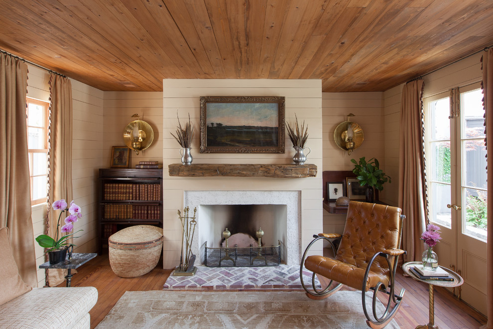 Repräsentatives Landhaus Wohnzimmer mit beiger Wandfarbe, braunem Holzboden, Kamin und Kaminumrandung aus Beton in Charleston