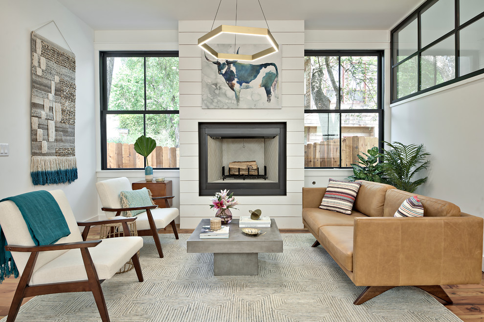 Repräsentatives, Fernseherloses Landhaus Wohnzimmer mit weißer Wandfarbe, hellem Holzboden, Kamin, Kaminumrandung aus Holz und braunem Boden in Austin