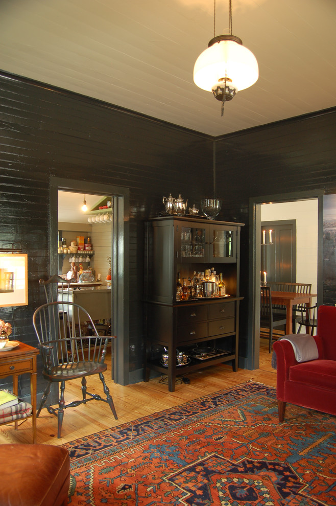 Пример оригинального дизайна: гостиная комната в стиле кантри с черными стенами, паркетным полом среднего тона и ковром на полу