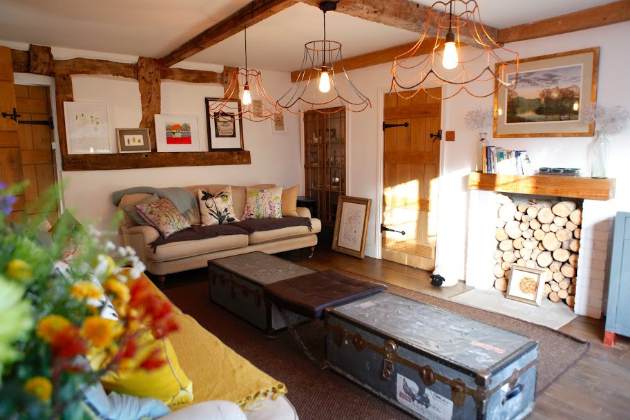 Imagen de salón de estilo de casa de campo con suelo de madera oscura, marco de chimenea de ladrillo y vigas vistas