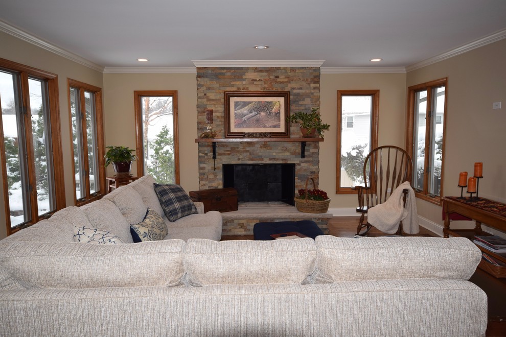 Photo of a medium sized farmhouse open plan living room in Chicago with beige walls, medium hardwood flooring, a standard fireplace, a stone fireplace surround, a wall mounted tv and brown floors.
