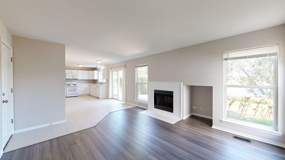 Cette photo montre un salon tendance de taille moyenne et fermé avec un mur gris, sol en stratifié, une cheminée standard, un manteau de cheminée en carrelage et un sol blanc.
