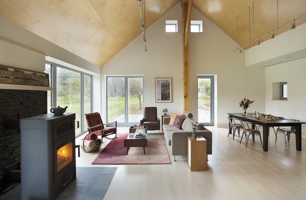 Esempio di un soggiorno country aperto con pareti bianche, parquet chiaro, stufa a legna, nessuna TV e sala formale