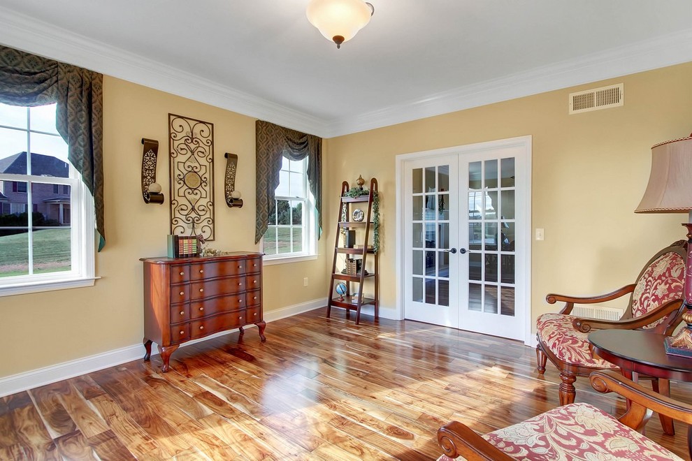 Imagen de biblioteca en casa cerrada tradicional de tamaño medio con paredes beige y suelo de madera en tonos medios