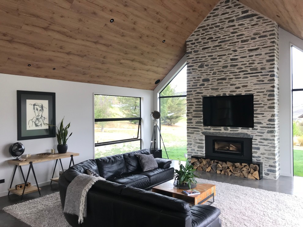 Inspiration for a large modern open concept concrete floor and black floor living room remodel in Other with white walls, a standard fireplace, a stone fireplace and a wall-mounted tv