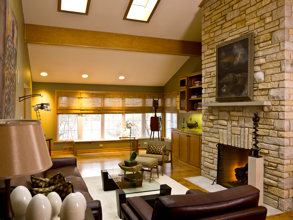 Imagen de salón actual con paredes verdes, todas las chimeneas y marco de chimenea de piedra