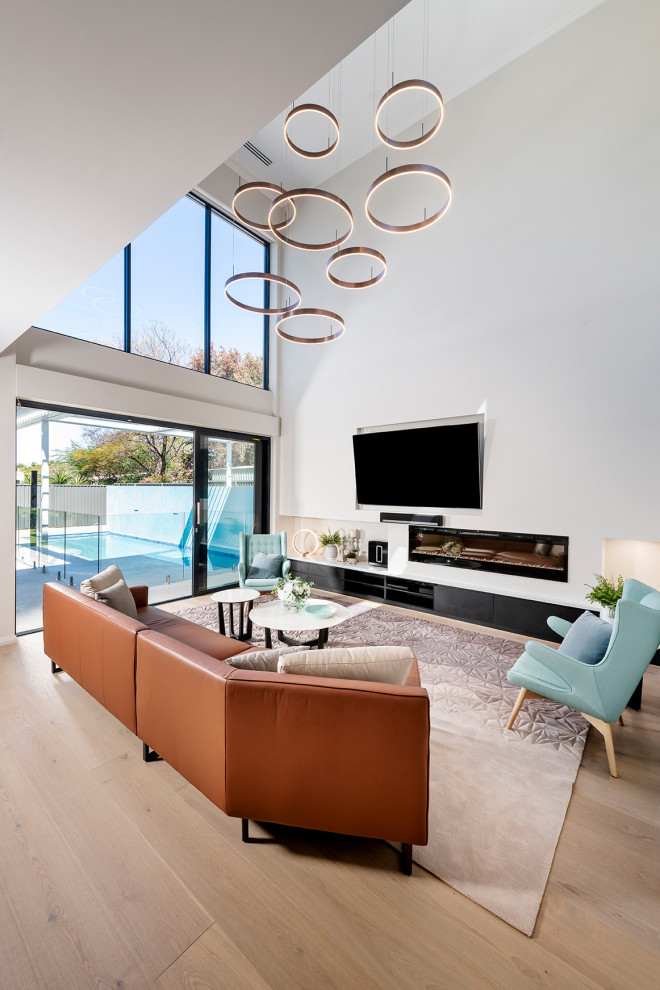 Geräumiges, Offenes Modernes Wohnzimmer mit weißer Wandfarbe, braunem Holzboden, Gaskamin, TV-Wand und beigem Boden in Perth