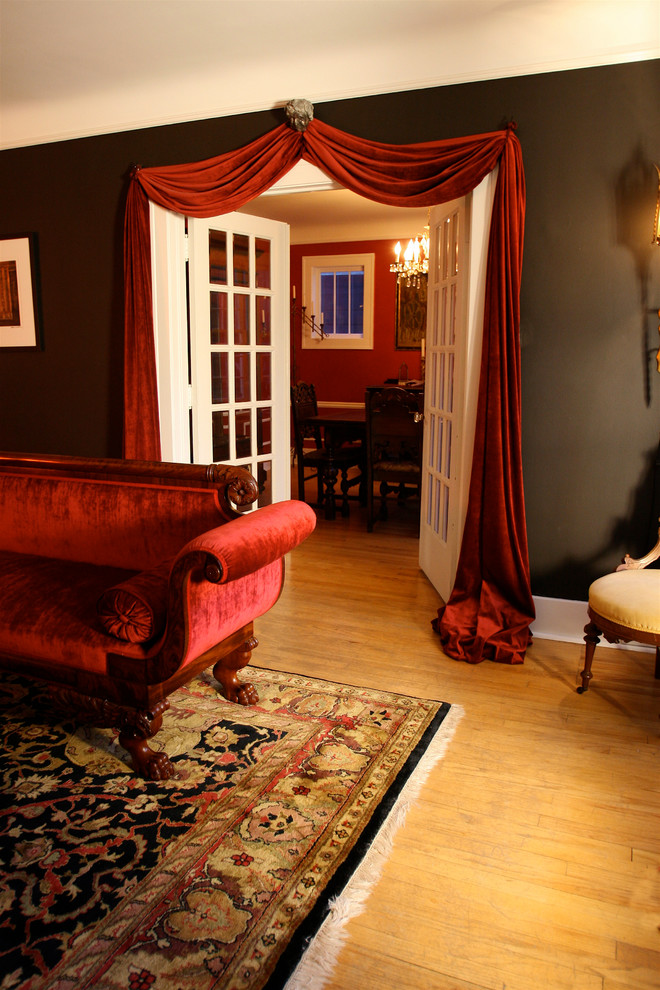 Esempio di un piccolo soggiorno chic chiuso con sala formale, pareti nere, parquet chiaro, camino classico, cornice del camino in legno e nessuna TV