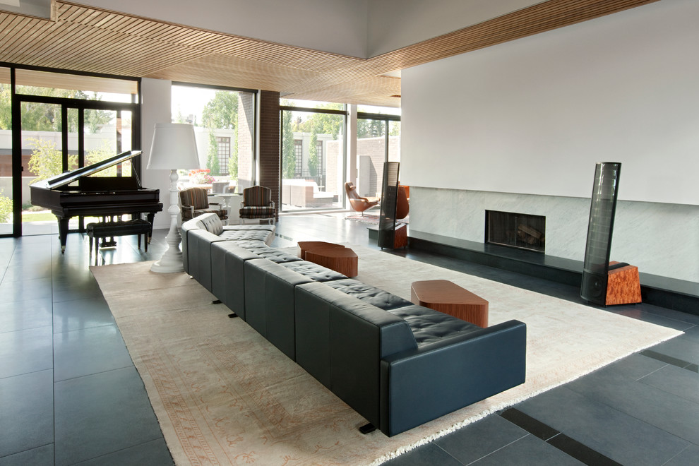 Example of a minimalist living room design in Calgary with white walls and a stone fireplace