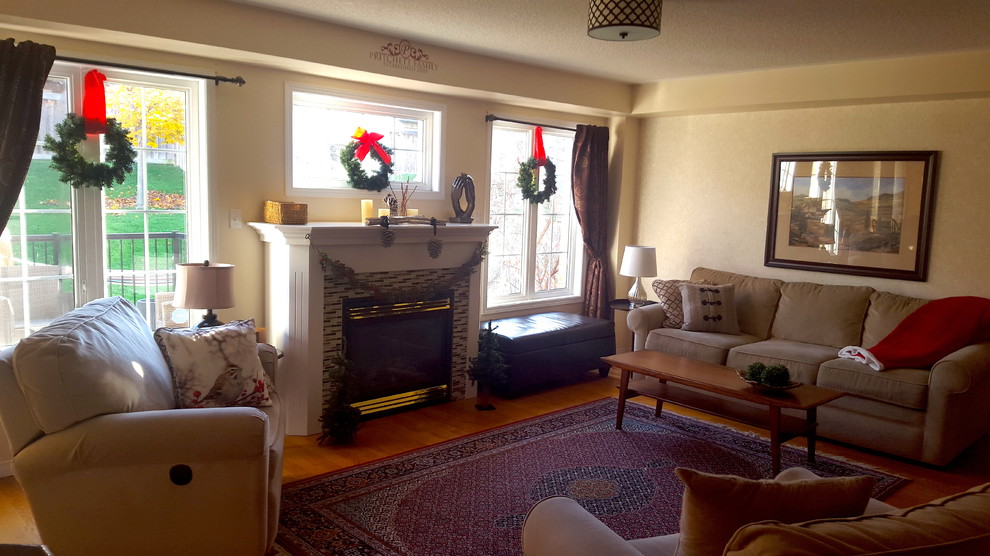 Photo of a medium sized traditional formal enclosed living room in Toronto with beige walls, medium hardwood flooring, no fireplace, a tiled fireplace surround, no tv and brown floors.