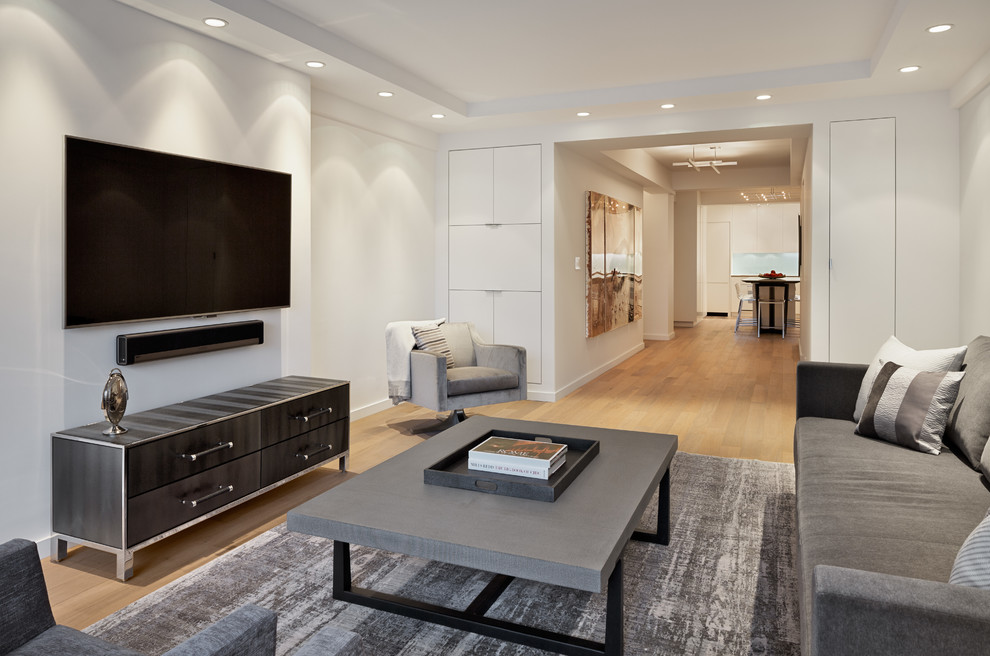 Photo of a medium sized contemporary enclosed living room in New York with white walls, light hardwood flooring, a wall mounted tv and no fireplace.