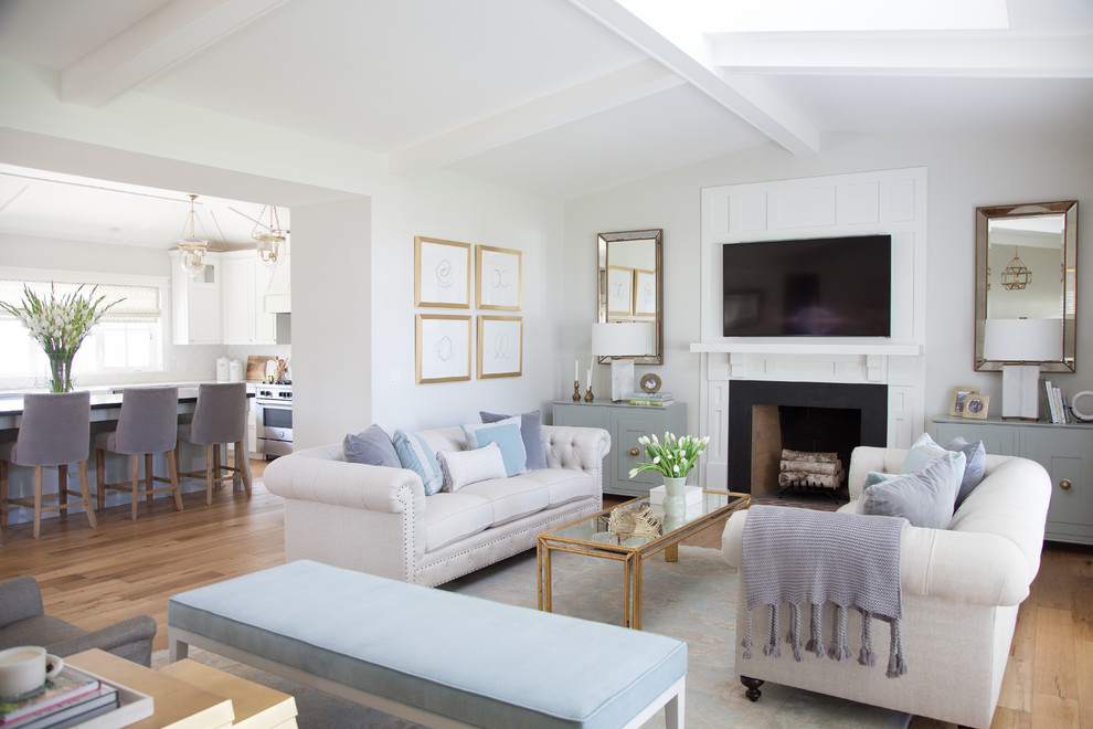 Idee per un soggiorno tradizionale con pareti bianche, pavimento in legno massello medio, camino classico e TV a parete