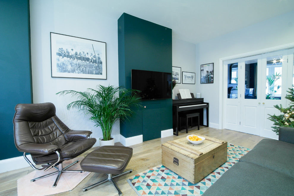 Diseño de salón para visitas abierto actual de tamaño medio sin chimenea con paredes verdes, suelo de madera en tonos medios y televisor independiente