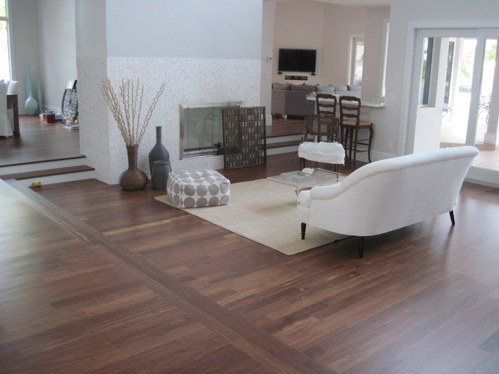 Immagine di un grande soggiorno contemporaneo aperto con pareti grigie, pavimento in legno massello medio, camino classico e TV a parete