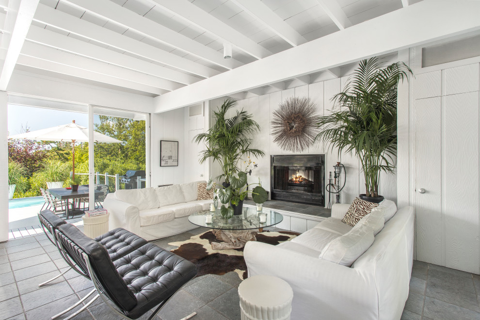Inspiration for a tropical open concept gray floor, exposed beam and wall paneling living room remodel in New York with white walls and a standard fireplace