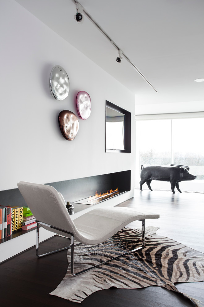 Diseño de salón con barra de bar abierto moderno con paredes blancas, suelo de madera oscura, chimenea lineal, marco de chimenea de piedra y televisor colgado en la pared