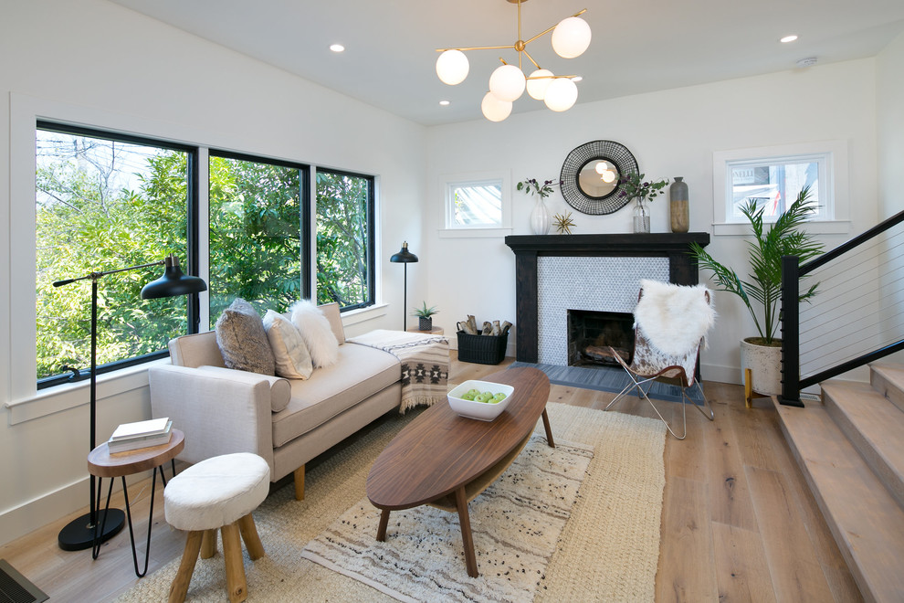 This is an example of a small contemporary open plan living room in San Francisco with white walls, light hardwood flooring, a standard fireplace and a tiled fireplace surround.