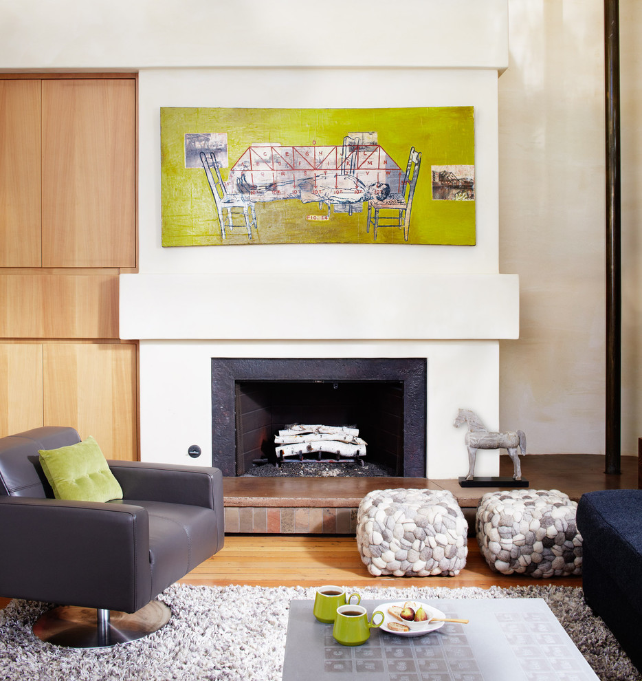 Cette photo montre un salon moderne avec un mur blanc, un sol en bois brun et une cheminée standard.
