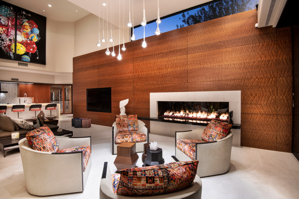 На фото: большая открытая гостиная комната в современном стиле с коричневыми стенами, двусторонним камином, фасадом камина из дерева, мультимедийным центром и белым полом
