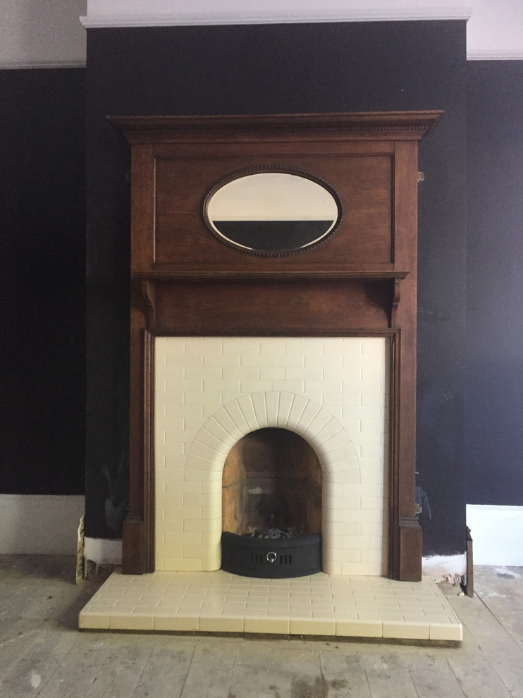 Modelo de salón cerrado, retro, de tamaño medio, sin televisor, con todas las chimeneas, marco de chimenea de madera, paredes azules y suelo de madera clara