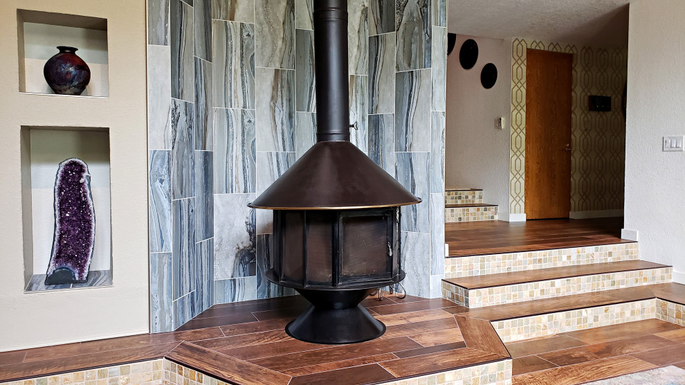 Ejemplo de salón actual con suelo de baldosas de porcelana, estufa de leña, marco de chimenea de baldosas y/o azulejos y suelo marrón