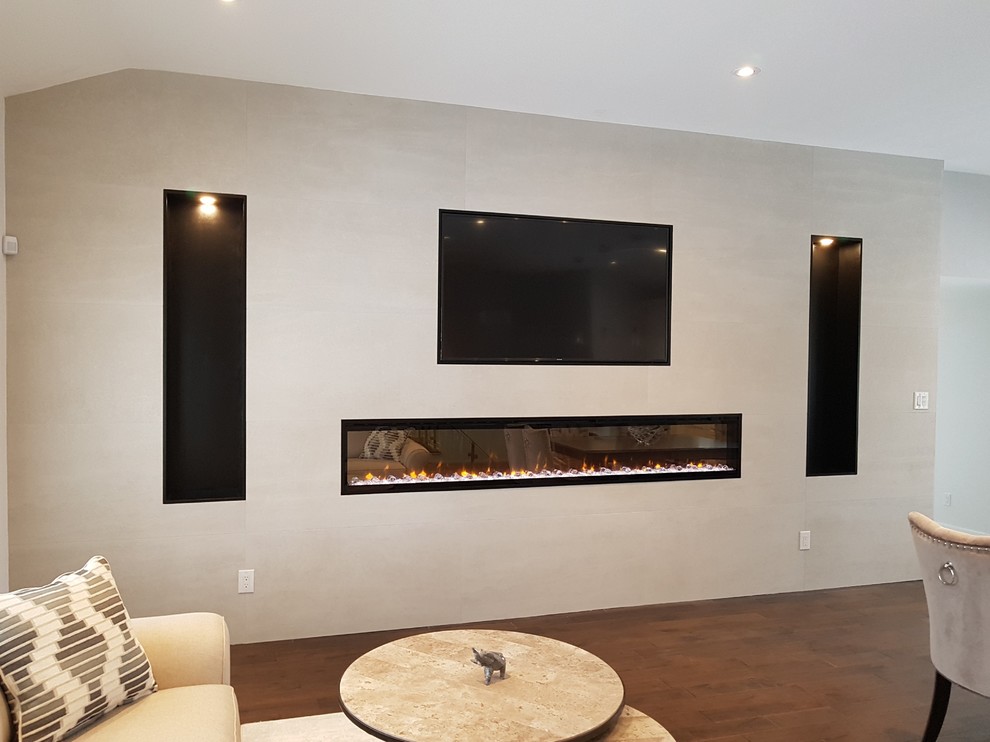 Cette image montre un salon minimaliste de taille moyenne et ouvert avec un mur gris, une cheminée ribbon, un manteau de cheminée en métal, un téléviseur fixé au mur, un sol marron et un sol en bois brun.