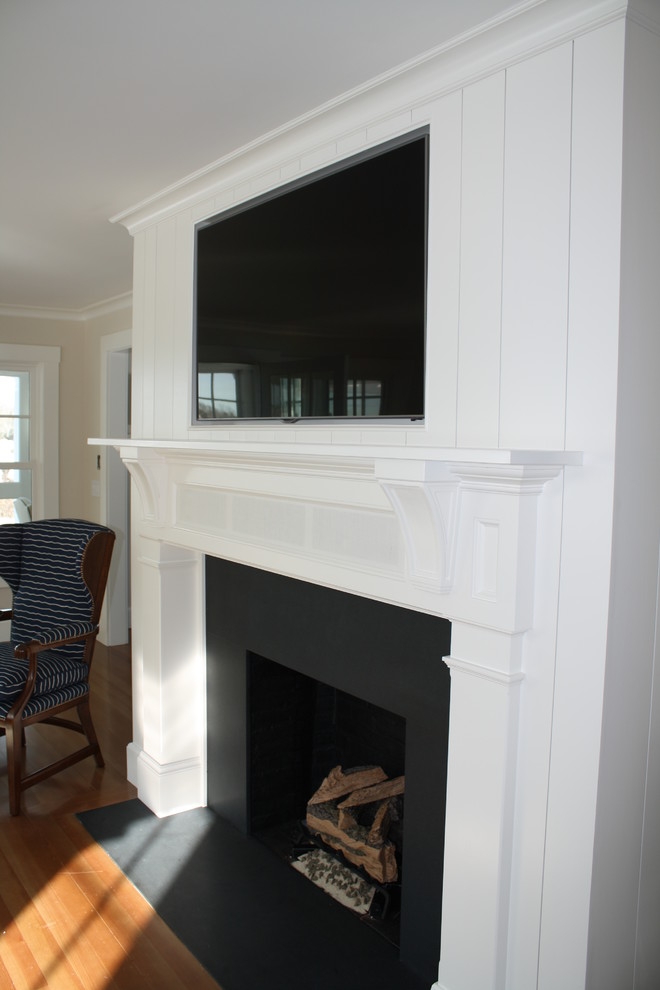 Cette photo montre un très grand salon chic ouvert avec un mur blanc, parquet clair, une cheminée standard, un manteau de cheminée en bois et un téléviseur fixé au mur.