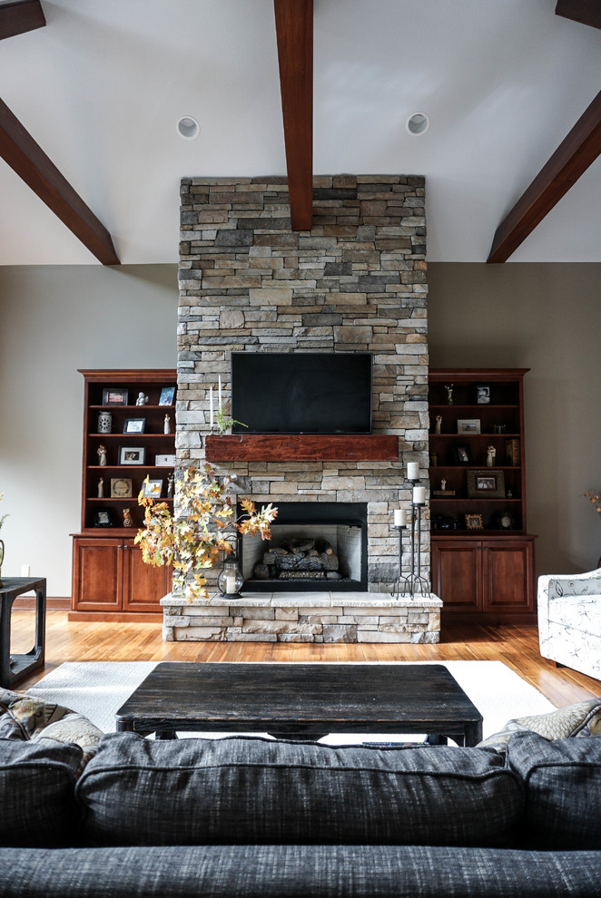 Inspiration for a medium sized country open plan living room in Other with grey walls, a standard fireplace, a stone fireplace surround, a wall mounted tv, brown floors and medium hardwood flooring.