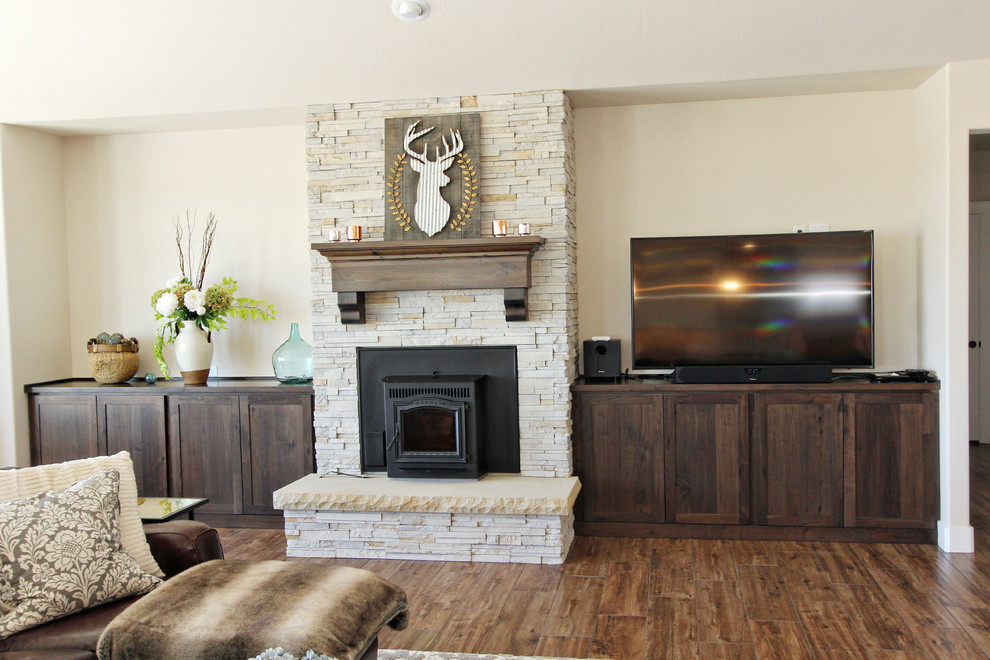 Cette image montre un salon craftsman de taille moyenne et ouvert avec un mur beige, un sol en bois brun, une cheminée standard, un manteau de cheminée en pierre et un téléviseur indépendant.