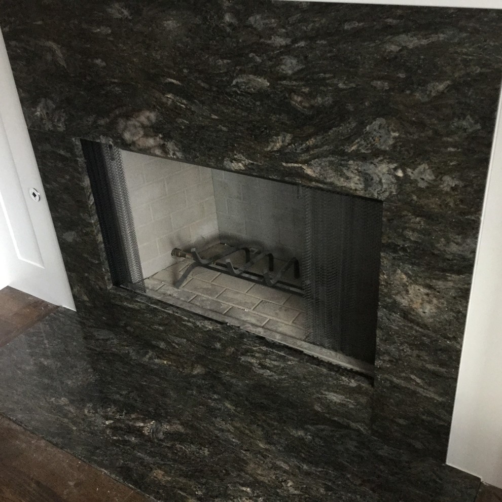ミルウォーキーにある低価格の小さなトランジショナルスタイルのおしゃれなリビング (白い壁、濃色無垢フローリング、標準型暖炉、石材の暖炉まわり、テレビなし) の写真