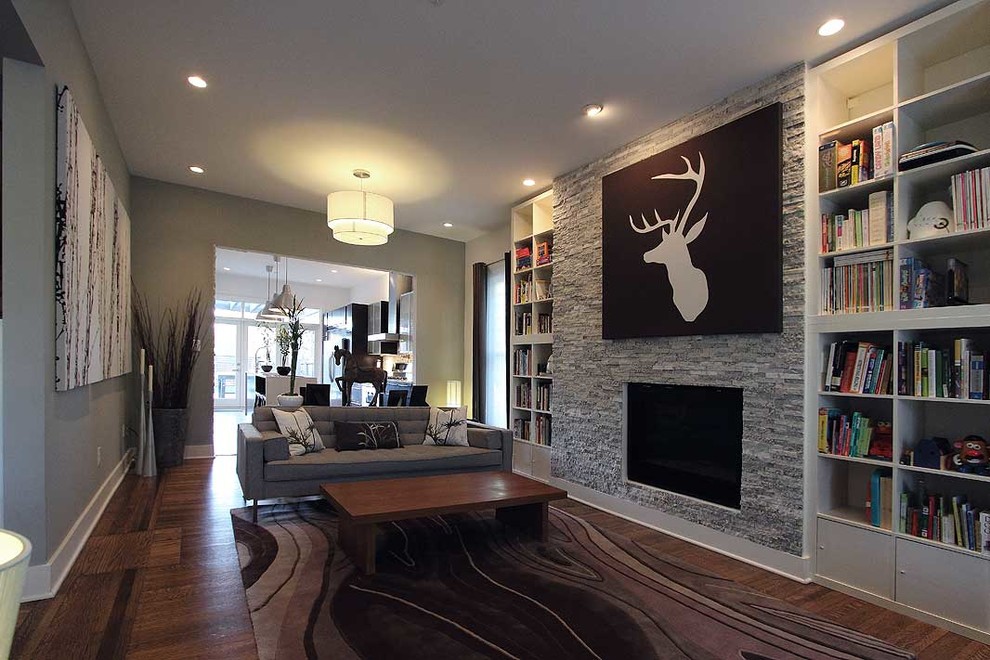 Großes, Repräsentatives Modernes Wohnzimmer mit grauer Wandfarbe, braunem Holzboden, Kamin, Kaminumrandung aus Stein und TV-Wand in Indianapolis