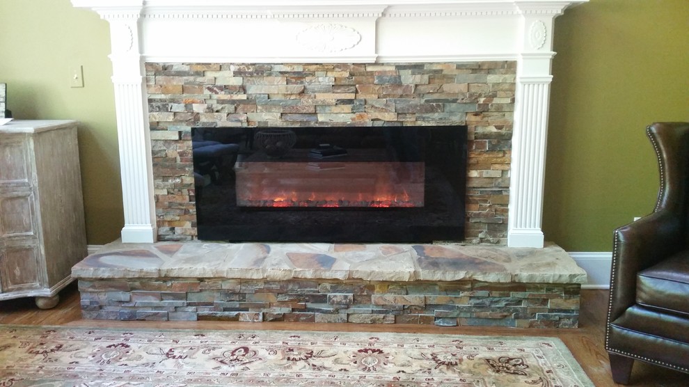 アトランタにあるお手頃価格のトラディショナルスタイルのおしゃれなリビング (緑の壁、淡色無垢フローリング、横長型暖炉、石材の暖炉まわり) の写真