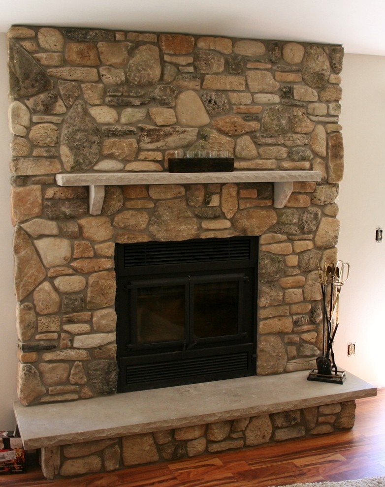 他の地域にあるお手頃価格のトラディショナルスタイルのおしゃれなLDK (白い壁、無垢フローリング、標準型暖炉、石材の暖炉まわり、テレビなし、茶色い床) の写真