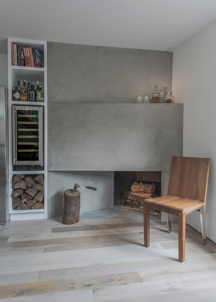 Idée de décoration pour un petit salon nordique fermé avec un mur blanc, parquet clair, une cheminée d'angle, un manteau de cheminée en béton, aucun téléviseur et un sol beige.