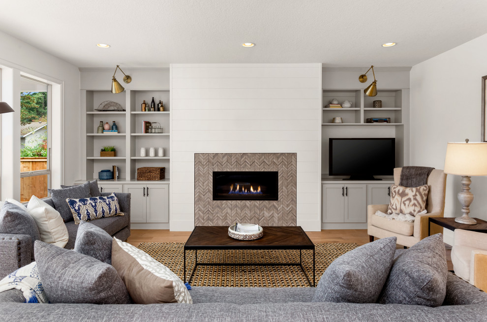 ロサンゼルスにある高級な中くらいなトランジショナルスタイルのおしゃれなLDK (白い壁、無垢フローリング、横長型暖炉、タイルの暖炉まわり、据え置き型テレビ、茶色い床) の写真