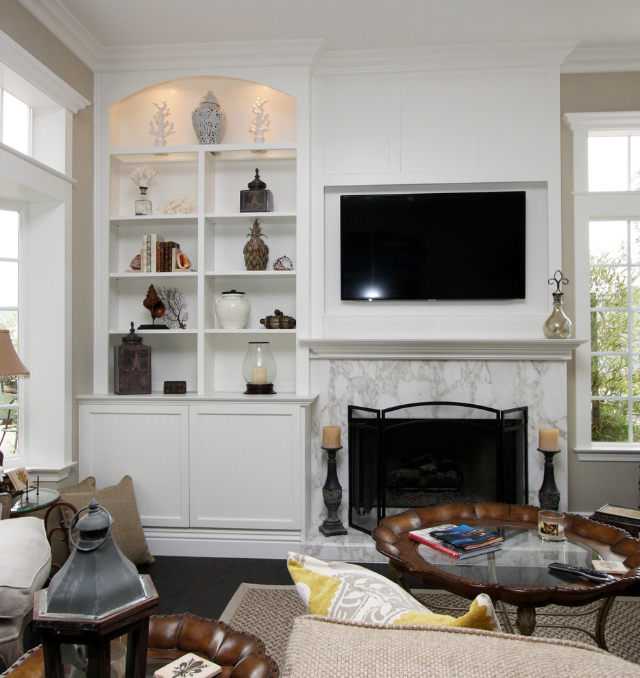 Mittelgroßes, Offenes Klassisches Wohnzimmer mit beiger Wandfarbe, dunklem Holzboden, Kamin, Kaminumrandung aus Stein und TV-Wand in Orange County