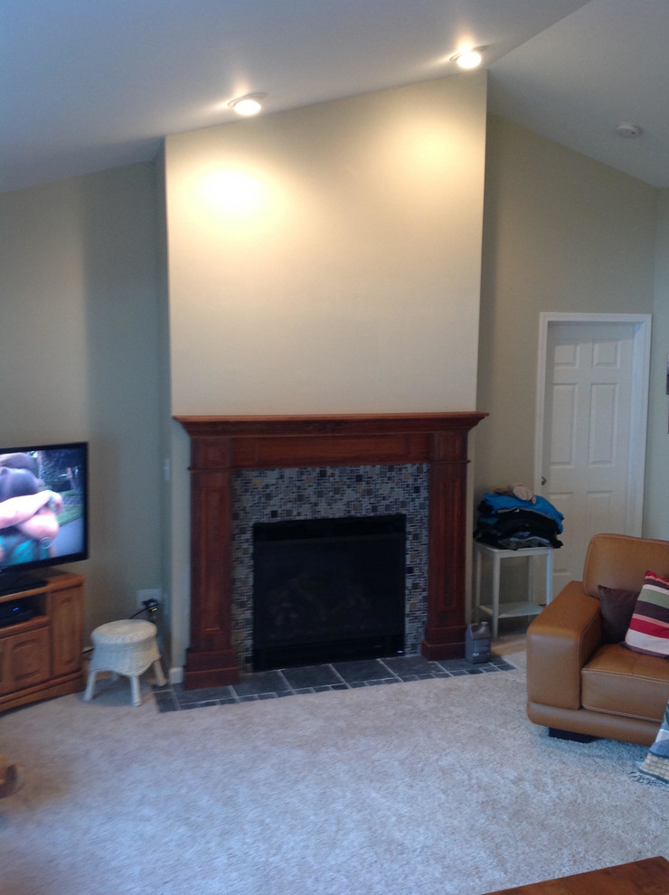 Photo of a medium sized traditional enclosed living room in St Louis with beige walls, carpet, a standard fireplace, a tiled fireplace surround, a freestanding tv and beige floors.