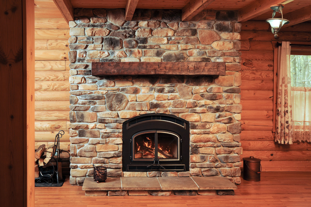 クリーブランドにある中くらいなトラディショナルスタイルのおしゃれなリビング (茶色い壁、濃色無垢フローリング、標準型暖炉、石材の暖炉まわり、テレビなし、茶色い床) の写真