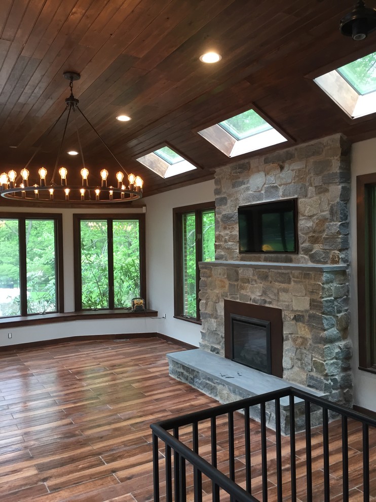 Inspiration for a mid-sized craftsman enclosed porcelain tile and brown floor living room remodel in Philadelphia with gray walls, a standard fireplace, a wood fireplace surround and a media wall