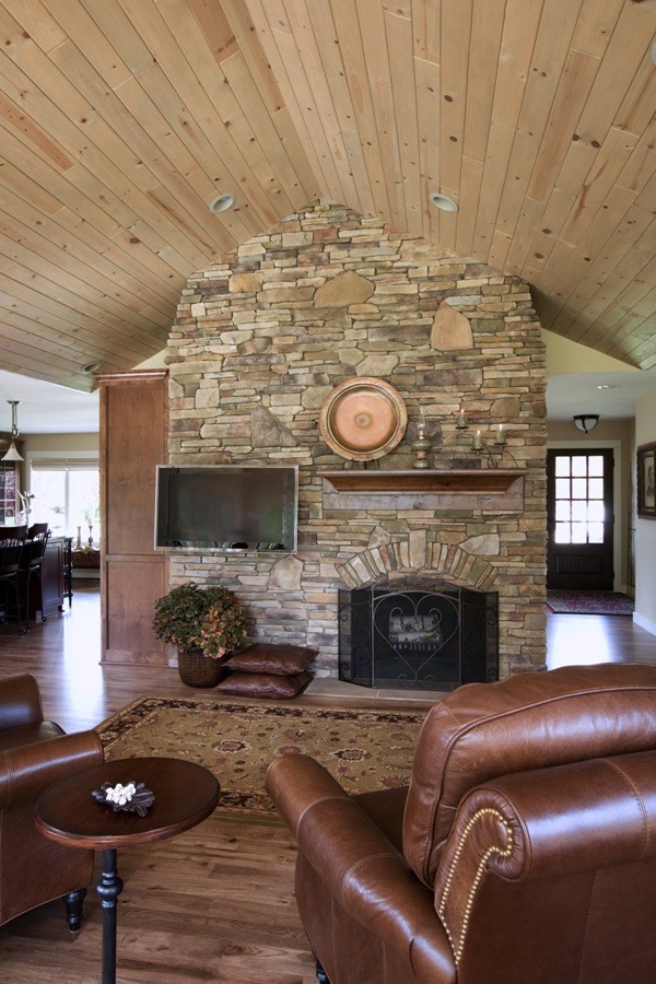 Immagine di un soggiorno classico aperto con stufa a legna, cornice del camino in pietra, pareti beige, pavimento in legno massello medio e TV a parete