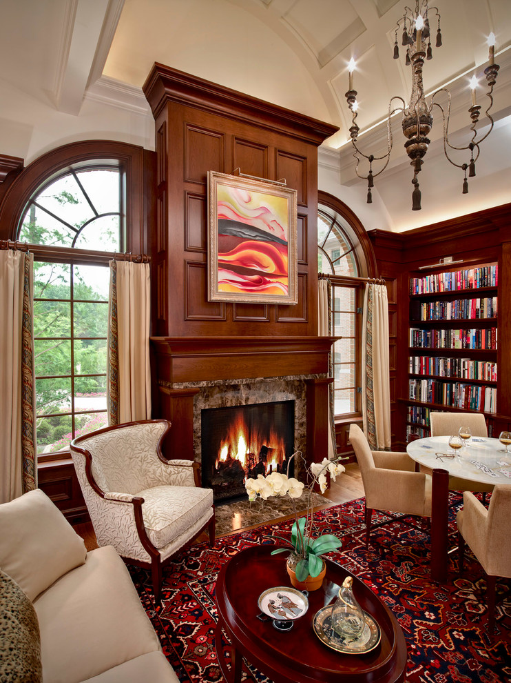 Foto di un soggiorno tradizionale con libreria, pavimento in legno massello medio e camino classico
