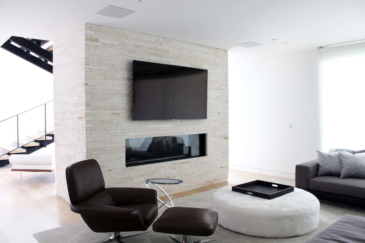 Exempel på ett mellanstort modernt allrum med öppen planlösning, med vita väggar, ljust trägolv, en bred öppen spis, en spiselkrans i sten, en väggmonterad TV och blått golv