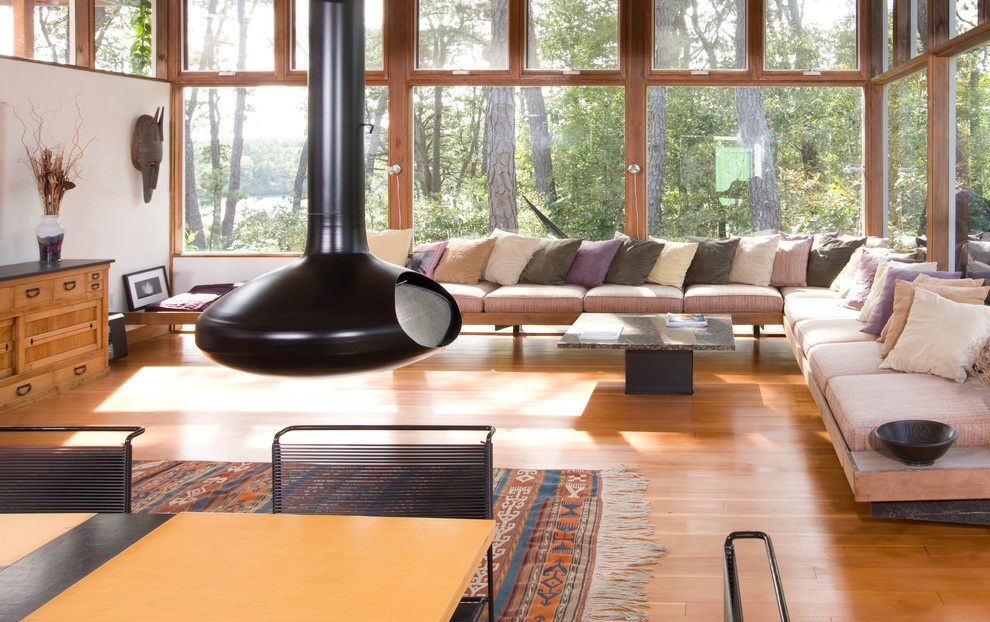 Réalisation d'un salon minimaliste ouvert avec une cheminée standard, un mur blanc et un sol en bois brun.