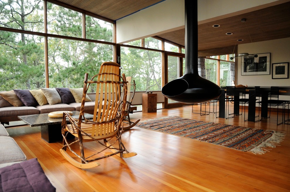 Minimalist open concept medium tone wood floor living room photo in Boston with a hanging fireplace and beige walls
