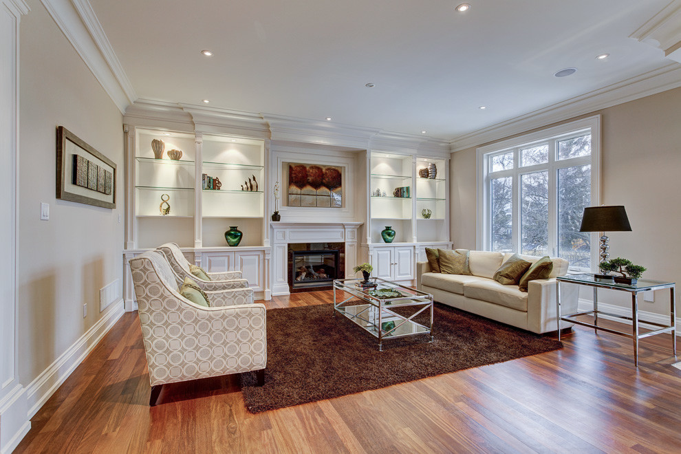 Fernseherloses, Mittelgroßes, Repräsentatives, Offenes Klassisches Wohnzimmer mit beiger Wandfarbe, braunem Holzboden, Kamin, Kaminumrandung aus Stein und braunem Boden in Toronto